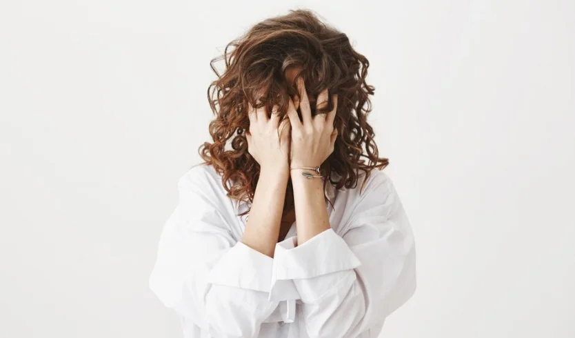 девушка с тревожностью закрывает лицо